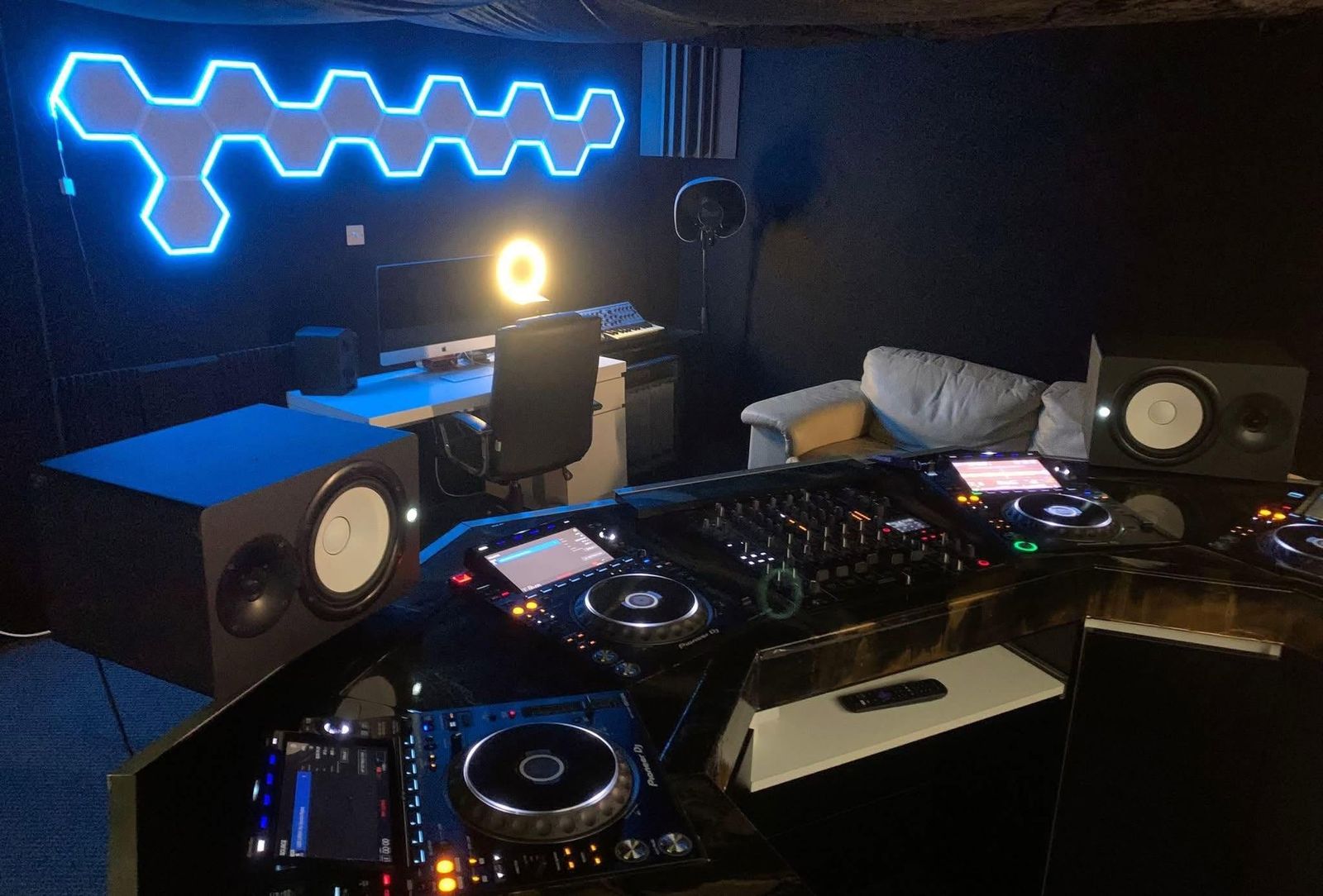 The DJ room at The EQ Lab: two Pioneer CDJs, a DJM-V10 mixer, monitor speakers and the production desk under blue hexagon lights