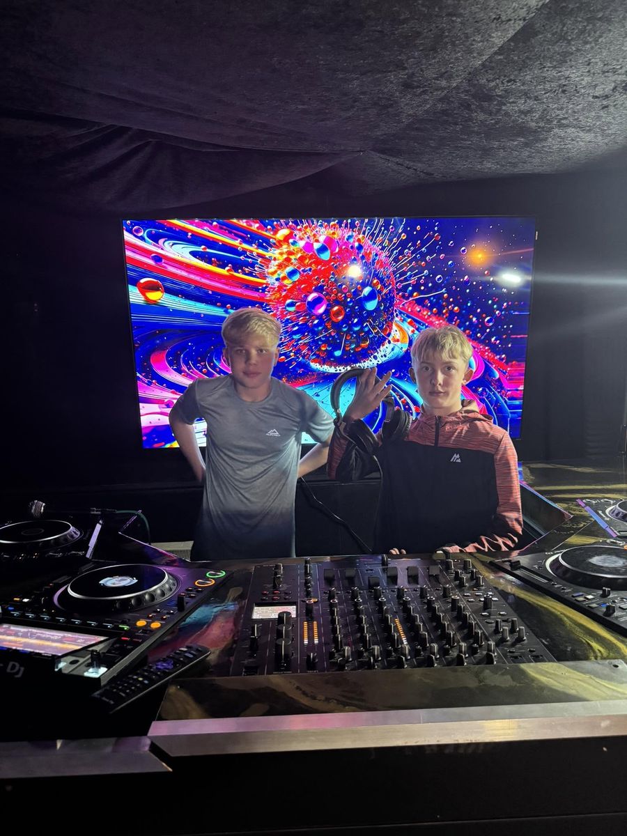 Two young people at the DJ decks in front of the visuals screen